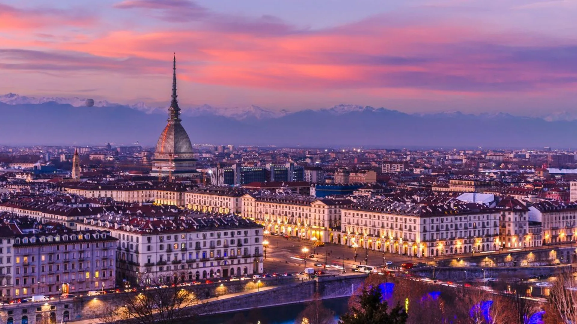 Piazza Vittorio Veneto e il centro di Torino illuminati al tramonto, con l'arco alpino sullo sfondo